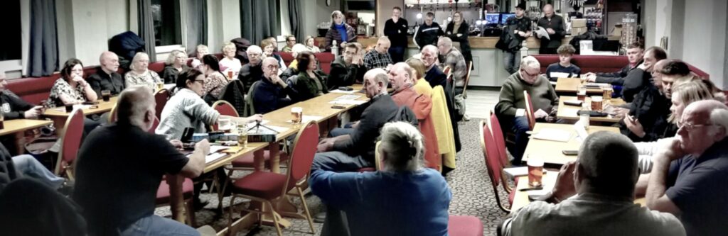 Residents Association Meeting at Warton Club, showing seated people and people standing at the edges of the bar.